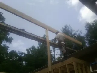 Carpenter setting a ridge beam over a new addition frame — Ice Dam Removal by Roofing Brothers in Mancelona