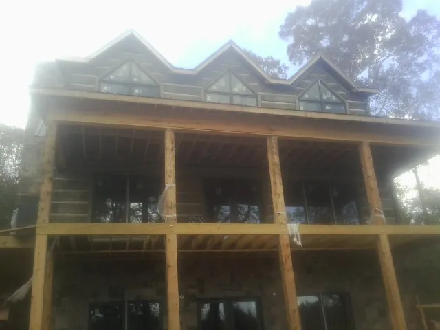 Dormers and porch framing on a large log home under construction — Roof Coating work by our crew in Mancelona