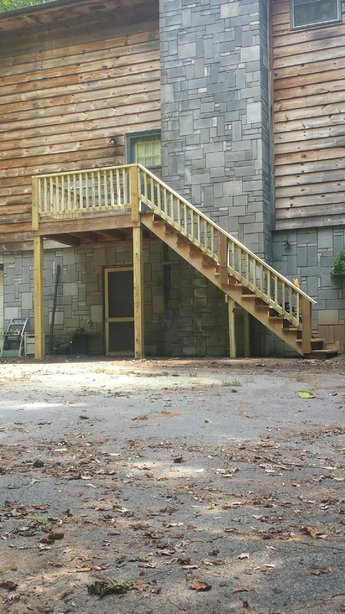 New pressure treated deck and stair landing on a log home in Mancelona