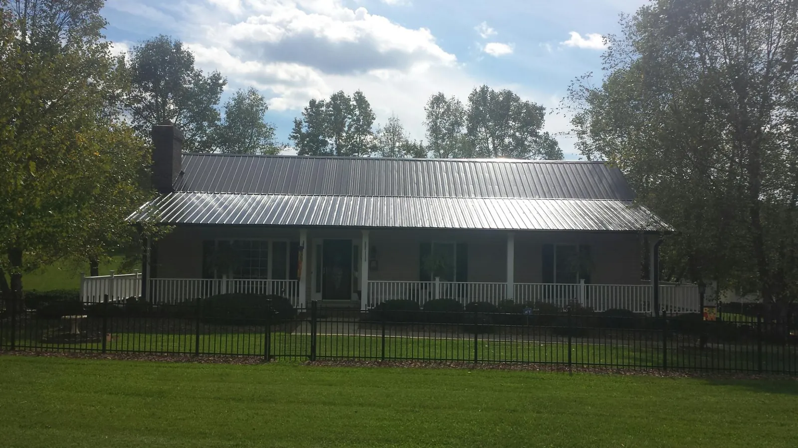Gray metal roof on a brick ranch with a full width front porch — Gutter Guard Installation work by our crew in Mancelona