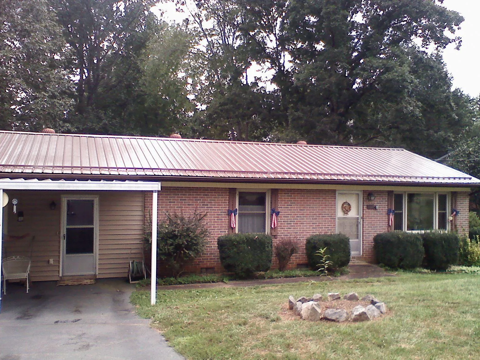 Bronze metal roof and carport on a brick ranch home — Roof Repair work by our crew in Mancelona